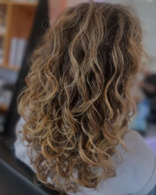 Halflang krullend haar in warm blond, geknipt volgens het krultype
